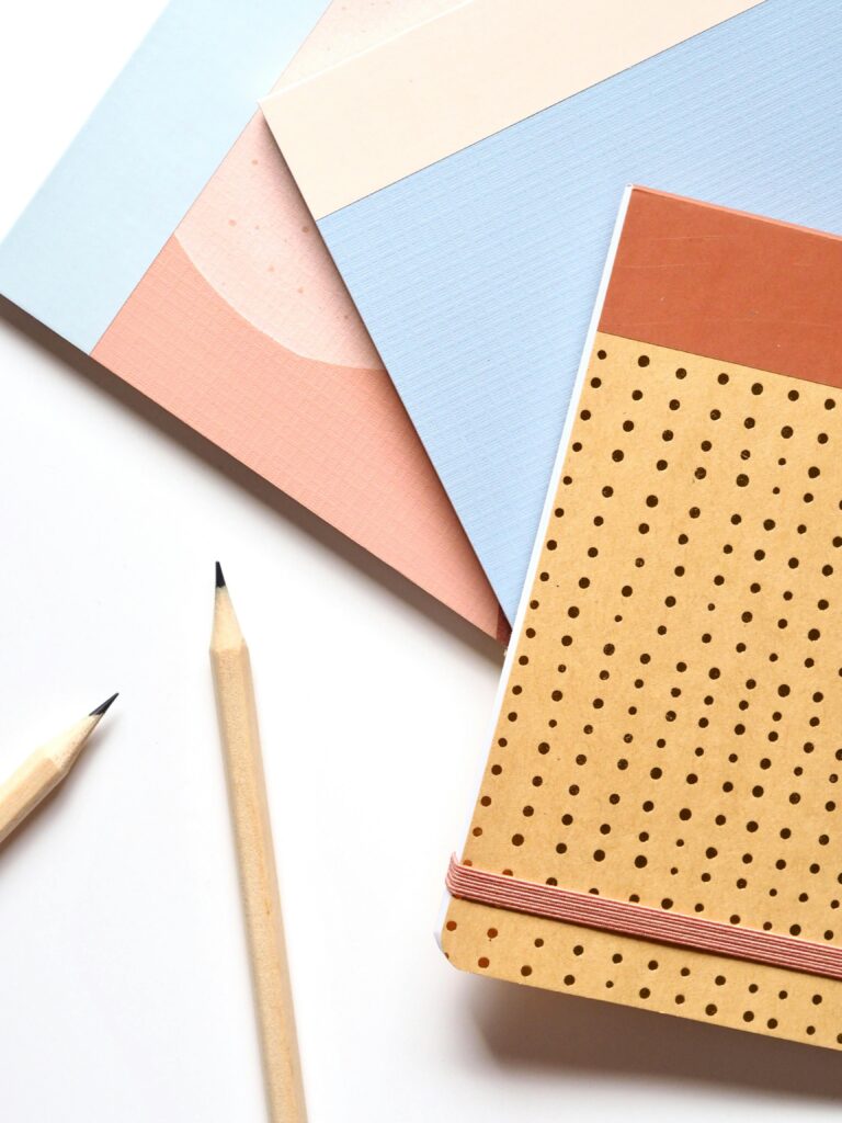 Colorful notebooks and pencils arranged neatly for a creative workspace.